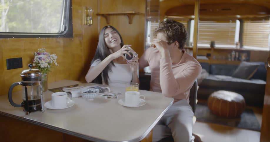 Woman laughs as she speaks with a man at a table