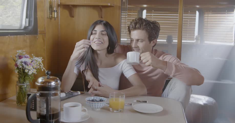 A man has his arm around a woman's shoulder as they eat and drink