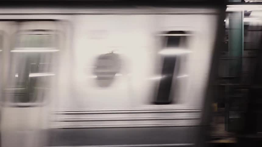 A woman is standing on a subway platform as a train passes by her