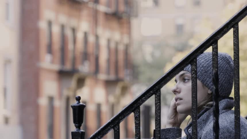 A woman sits on a city stoop