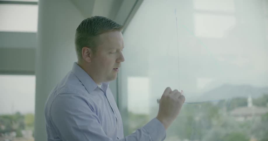A man is writing on a glass window