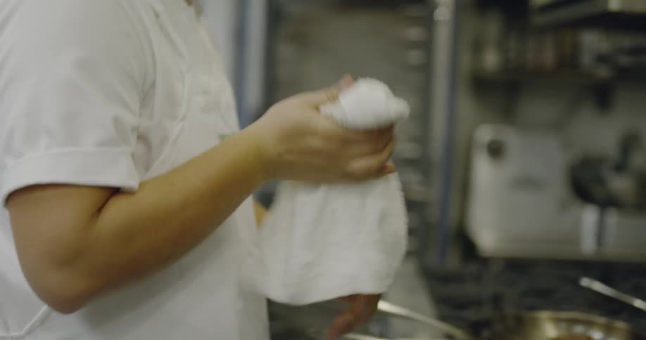 Cook wiping his hands on towel in kitchen