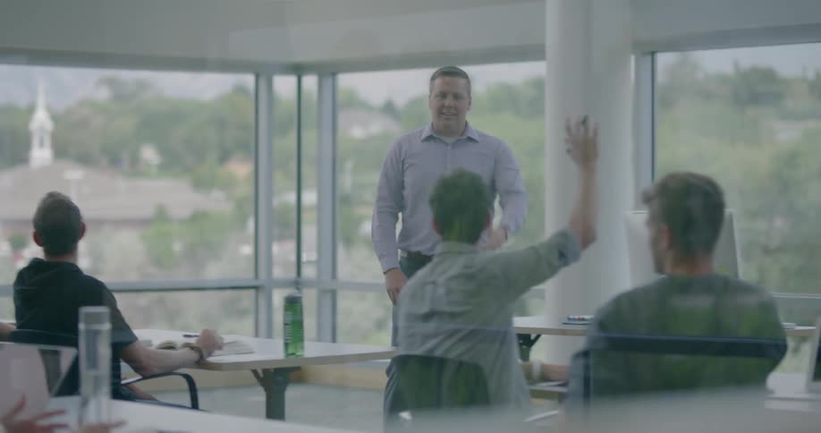 A man is leading a classroom of adults in an office building during the day
