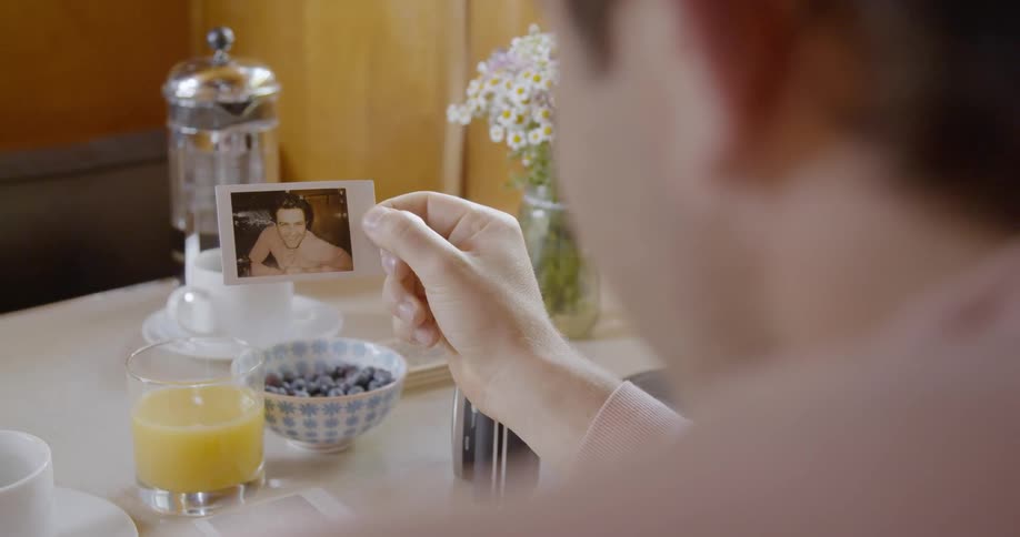 A man sitting at a table is looking at a photo