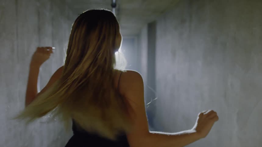 A woman with blonde hair is twirling down a hallway