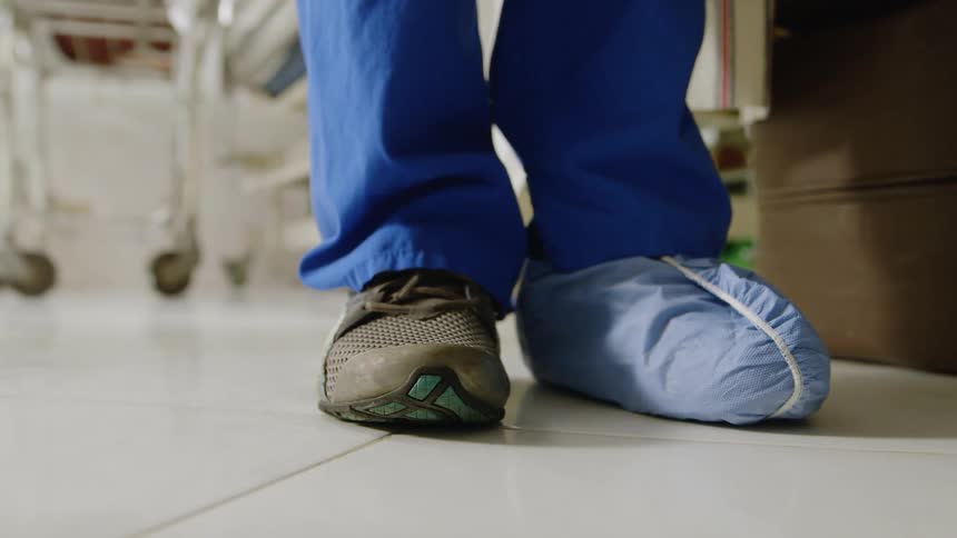 A doctor is putting protective covers over her shoes