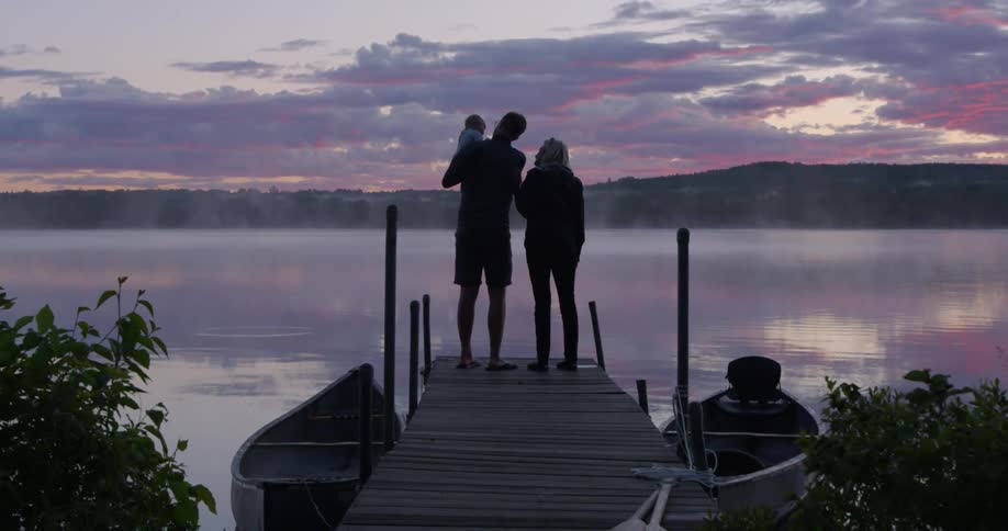 A family standing on a dock at sunrise