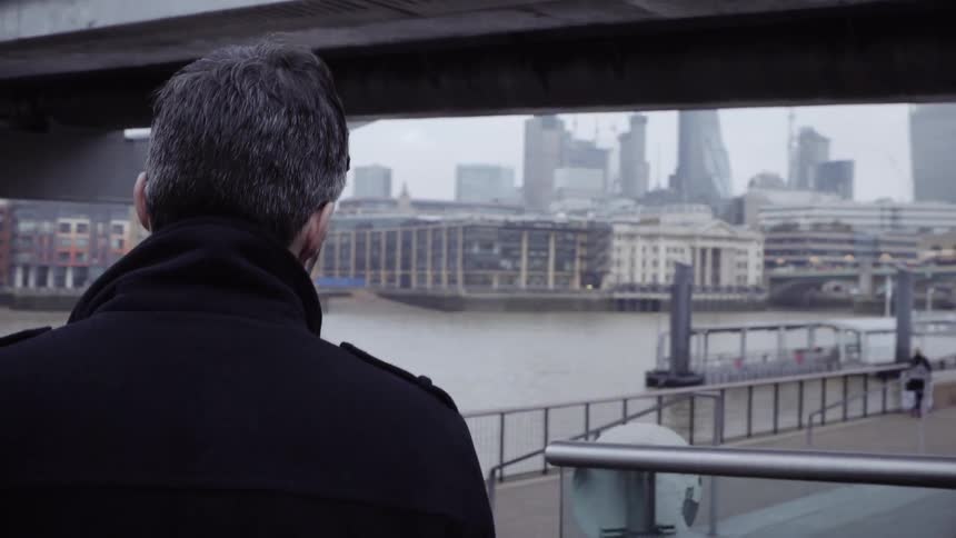 A man walks around a pier by a city