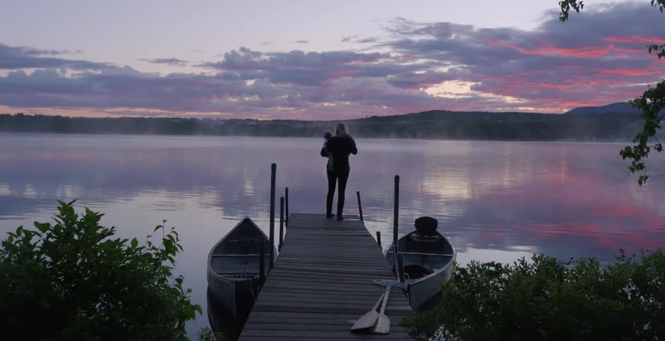A woman holds a child on a dock