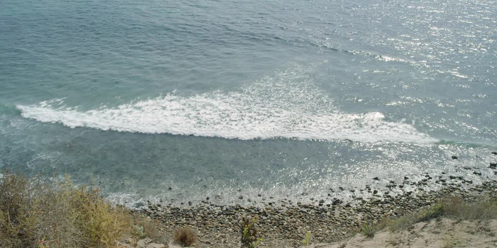 Frothy waves roll into the rocky shore