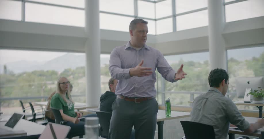 A man is standing in front of a bunch of people and talking to them