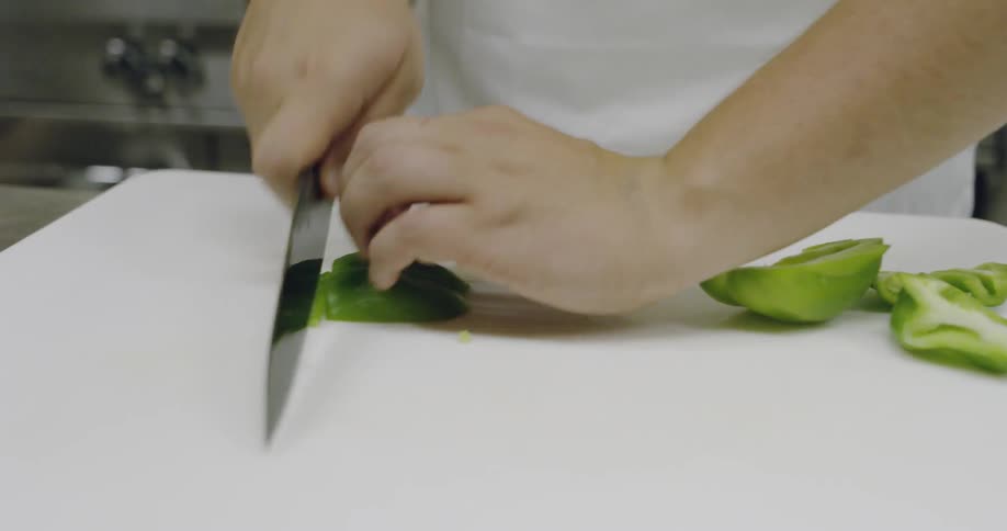A chef is cutting peppers in a kitchen