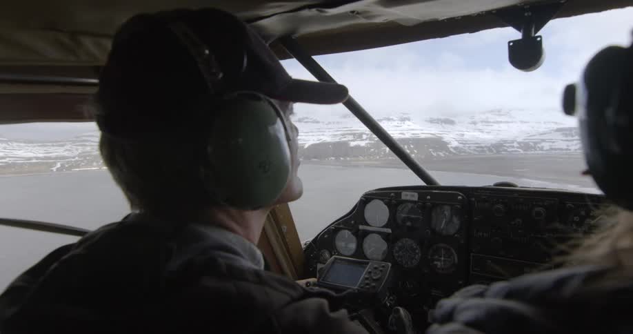 Two people are riding in an airplane over the lake