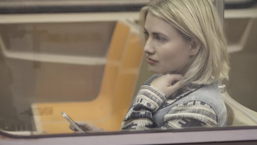 A woman sits in the train using her phone