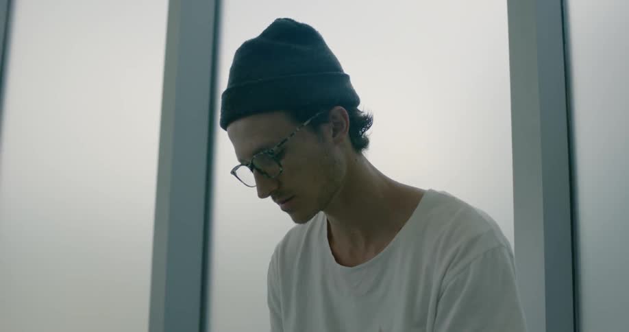 Man wearing a hat sits in front of a window