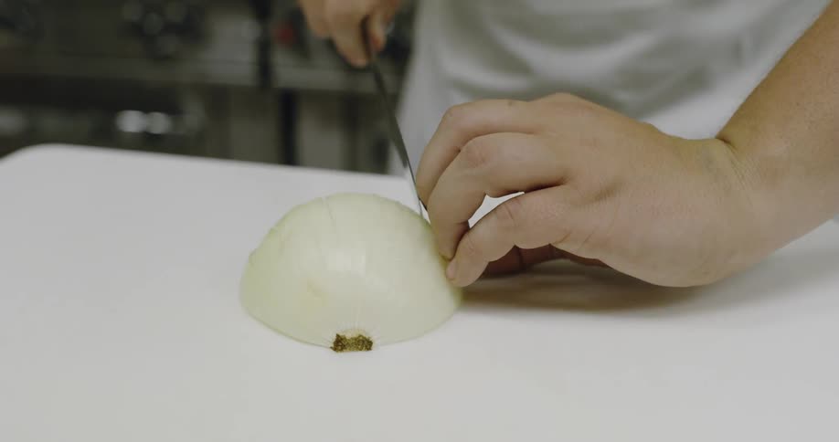A person cuts an onion on a table