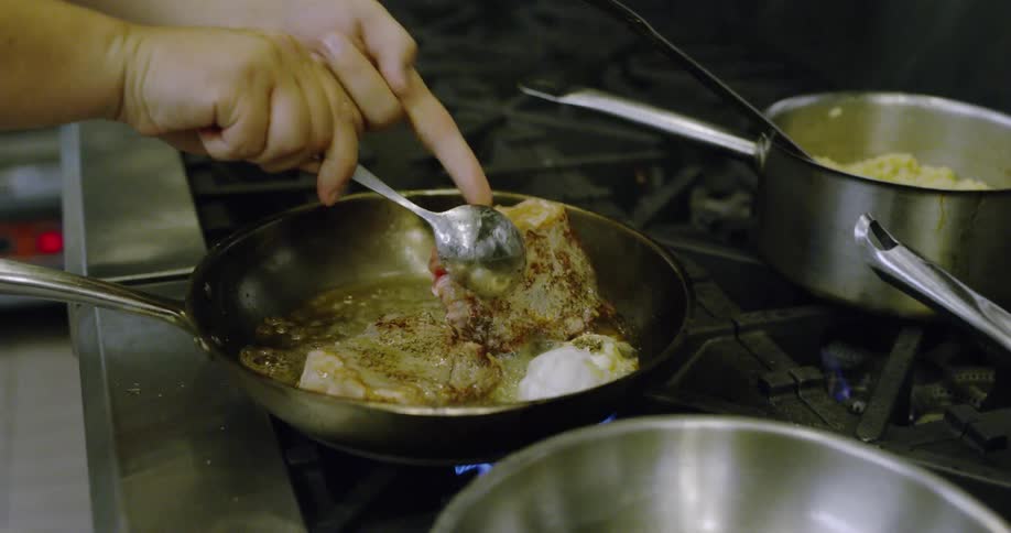 Person turns meat over in a frying pan