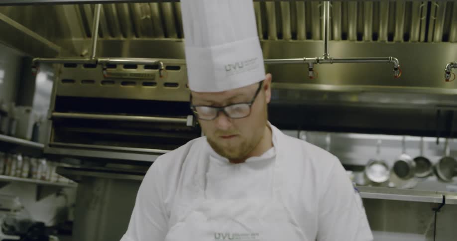 A chef is looking down preparing food in the kitchen