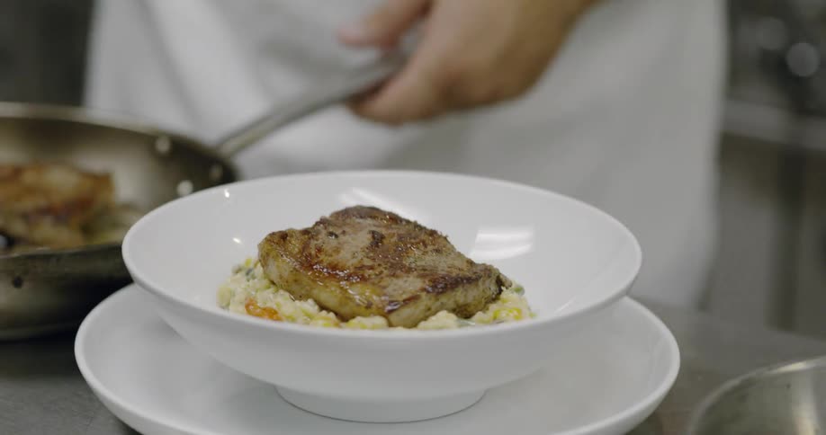 A chef places food in a bowl