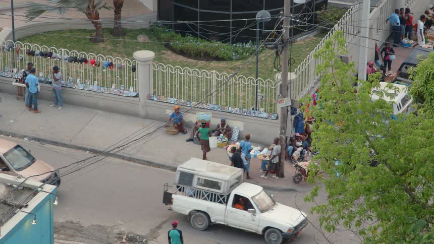 People and cars navigate a street corner in an african town