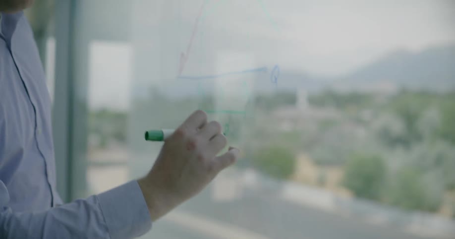 A man is writing a diagram on the window