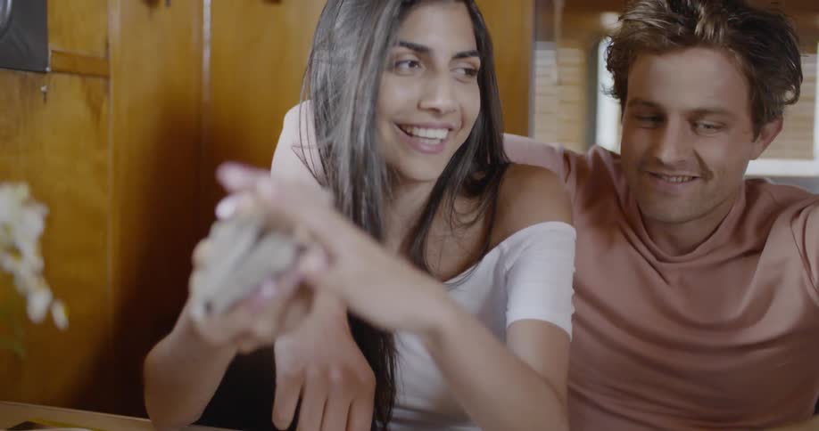 A woman shuffles cards as she sits and talks with a man who has his arm around her