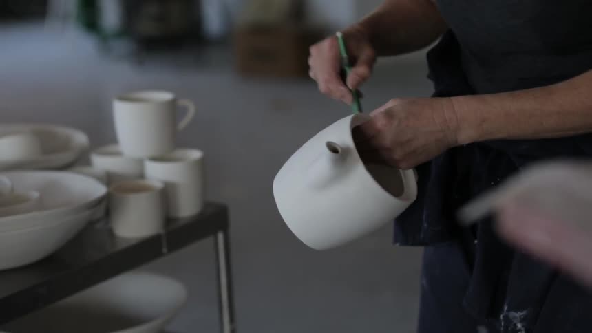 A woman creating a teapot in a studio