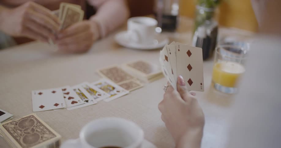 The two people are playing a game of cards on the table