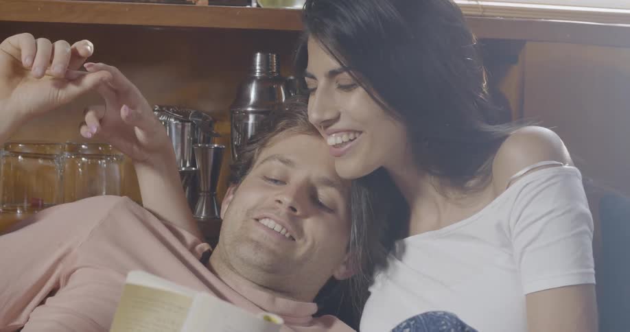 A man leans back against a woman as they talk and read during the day