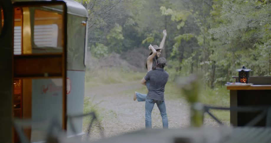 Man spins woman around in rainstorm