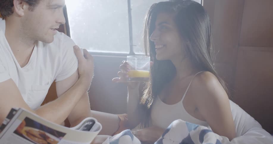 A man and woman are indoors reading and talking during the day