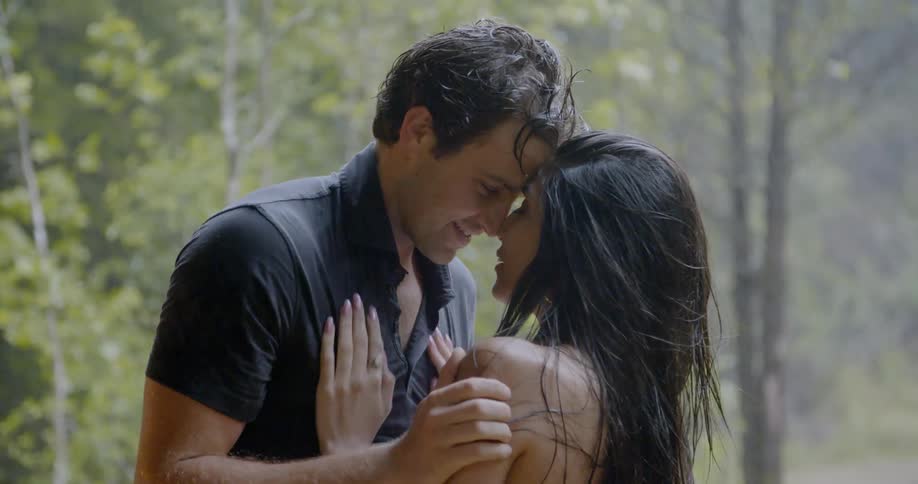 A man and woman are embracing and touching each other outside during a rain shower