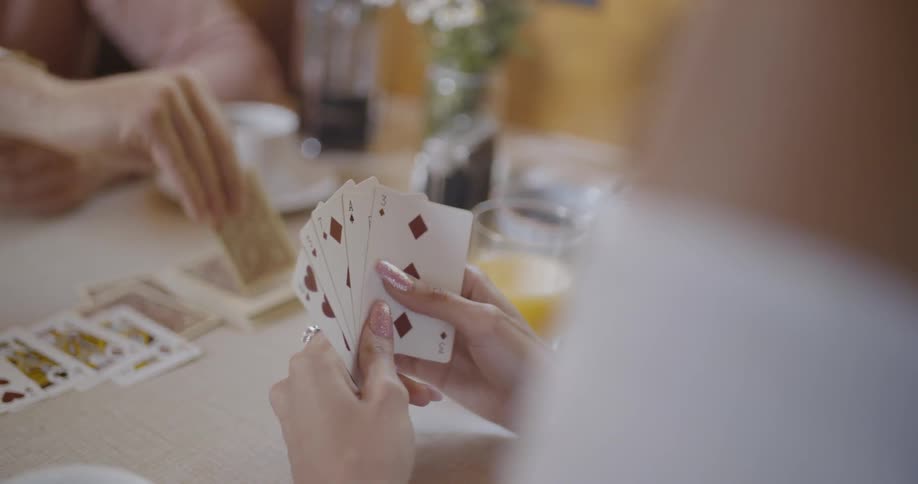 A man and woman are playing cards at a table inside