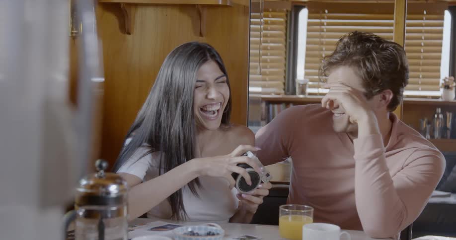 Woman laughs as she speaks with a man at a table
