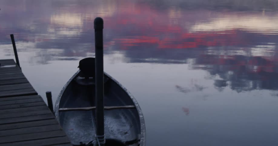 A small boat is docked near the pier of the lake
