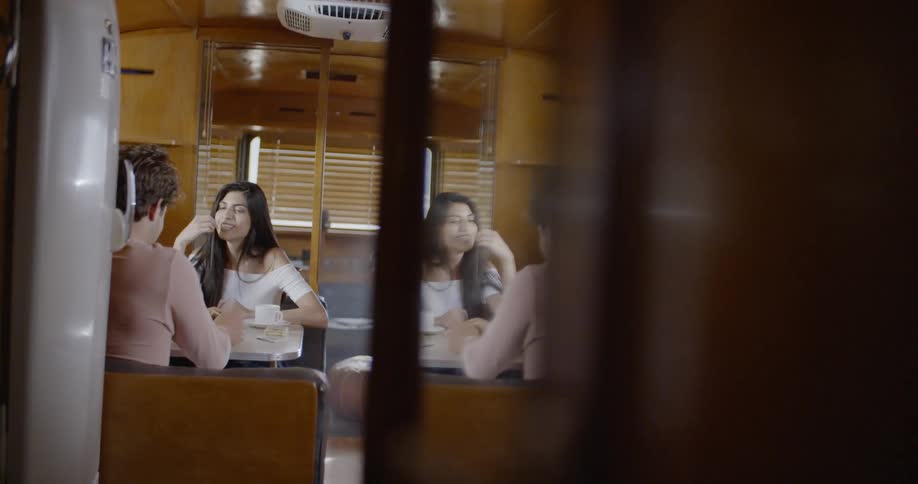 A man and woman are sitting and talking at a table in a camper trailer