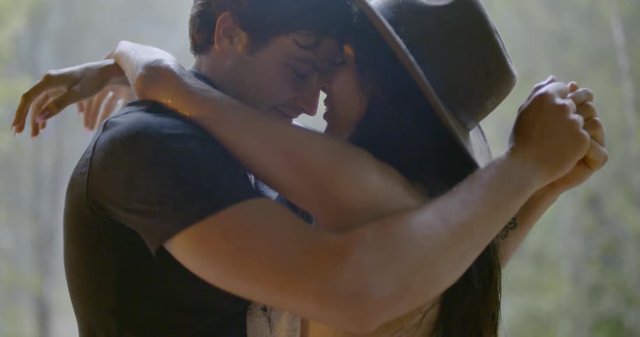 A man and woman are embracing outside while it rains