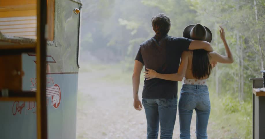 A man and woman hug next to a camper