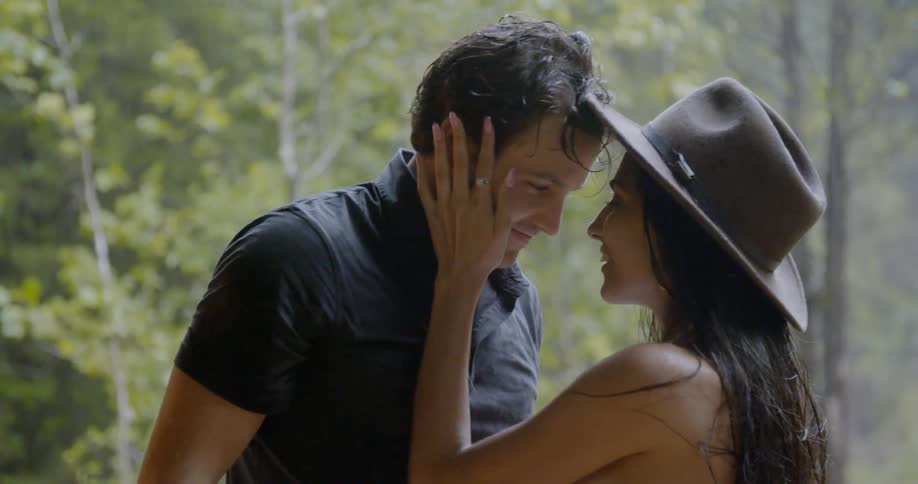 Man puts hat on woman's head then puts his face next to hers