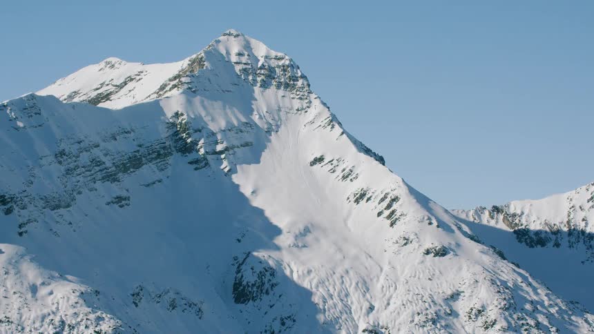 Snow covers mountain peaks and slopes on a sunny day