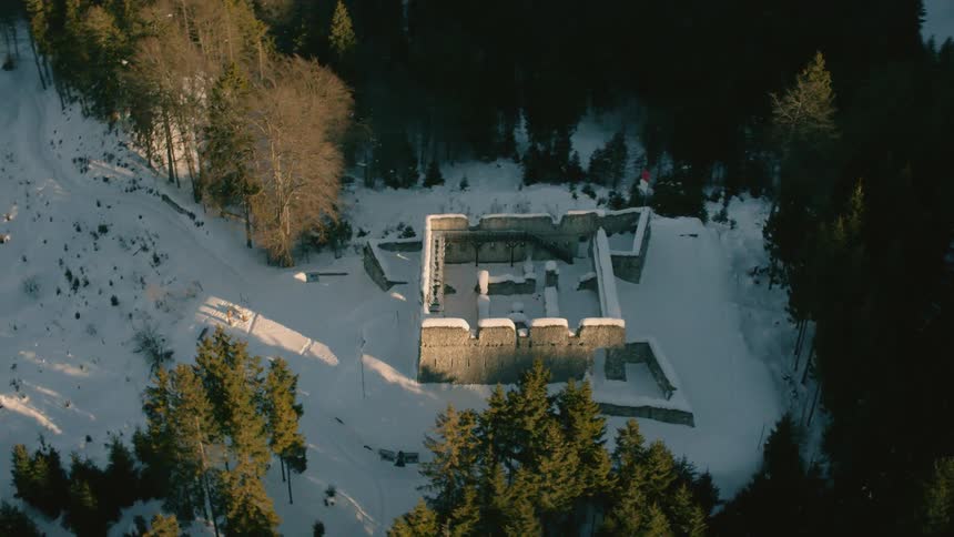 A ruined building on a mountainside sits covered in snow