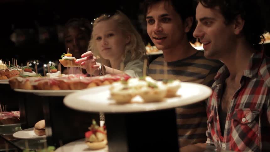 Four people choosing from a lot of appetizers