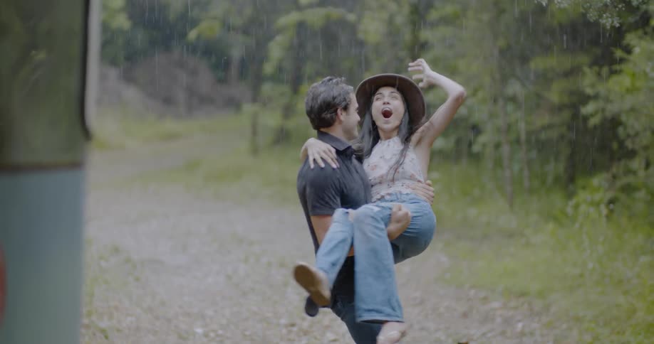 Man carries woman outside during rainstorm