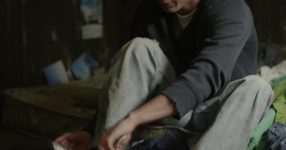 A teenage boy is putting on his shoes in a room in the morning