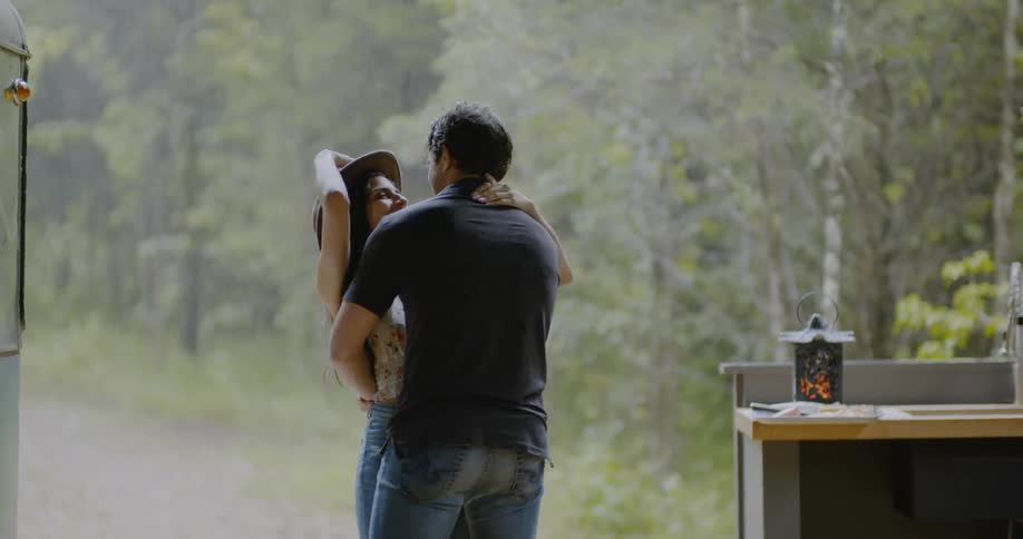 A couple hug and spin as they stand outside during a rain shower