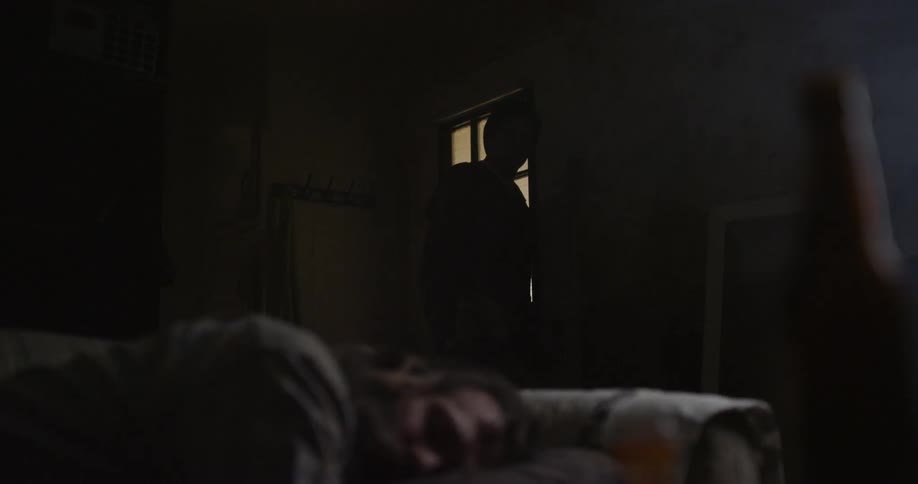 Man sleeps on a couch as another person leaves the room