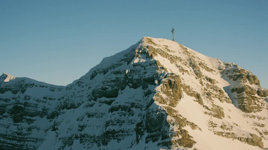 A cross is displayed on top of a snowy mountain