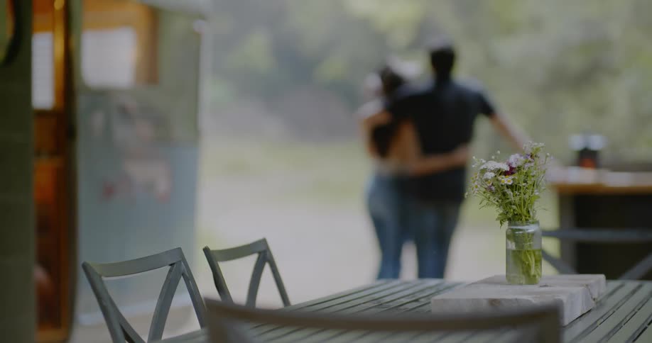 A man and woman hug next to a camper