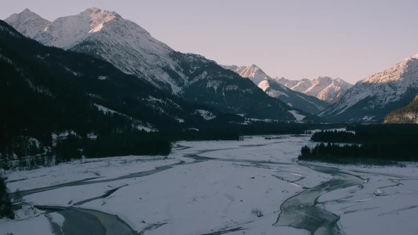 A melting river winds its way through a mountain valley
