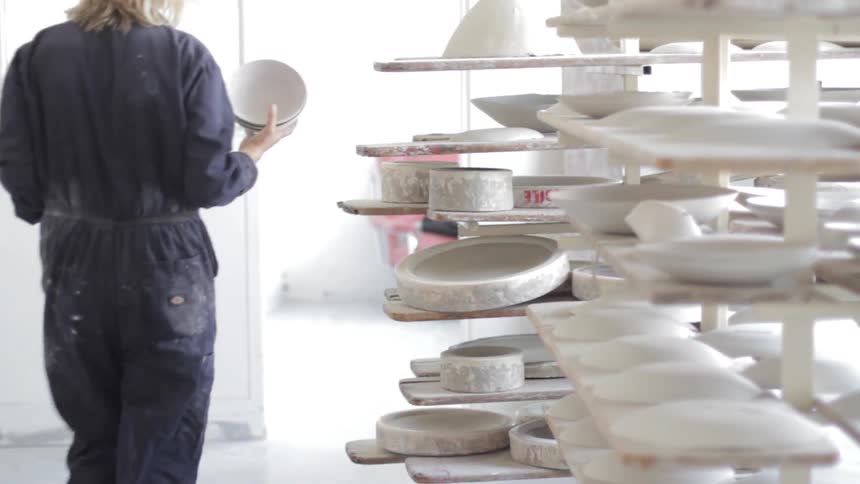 A woman walking by shelves of pottery